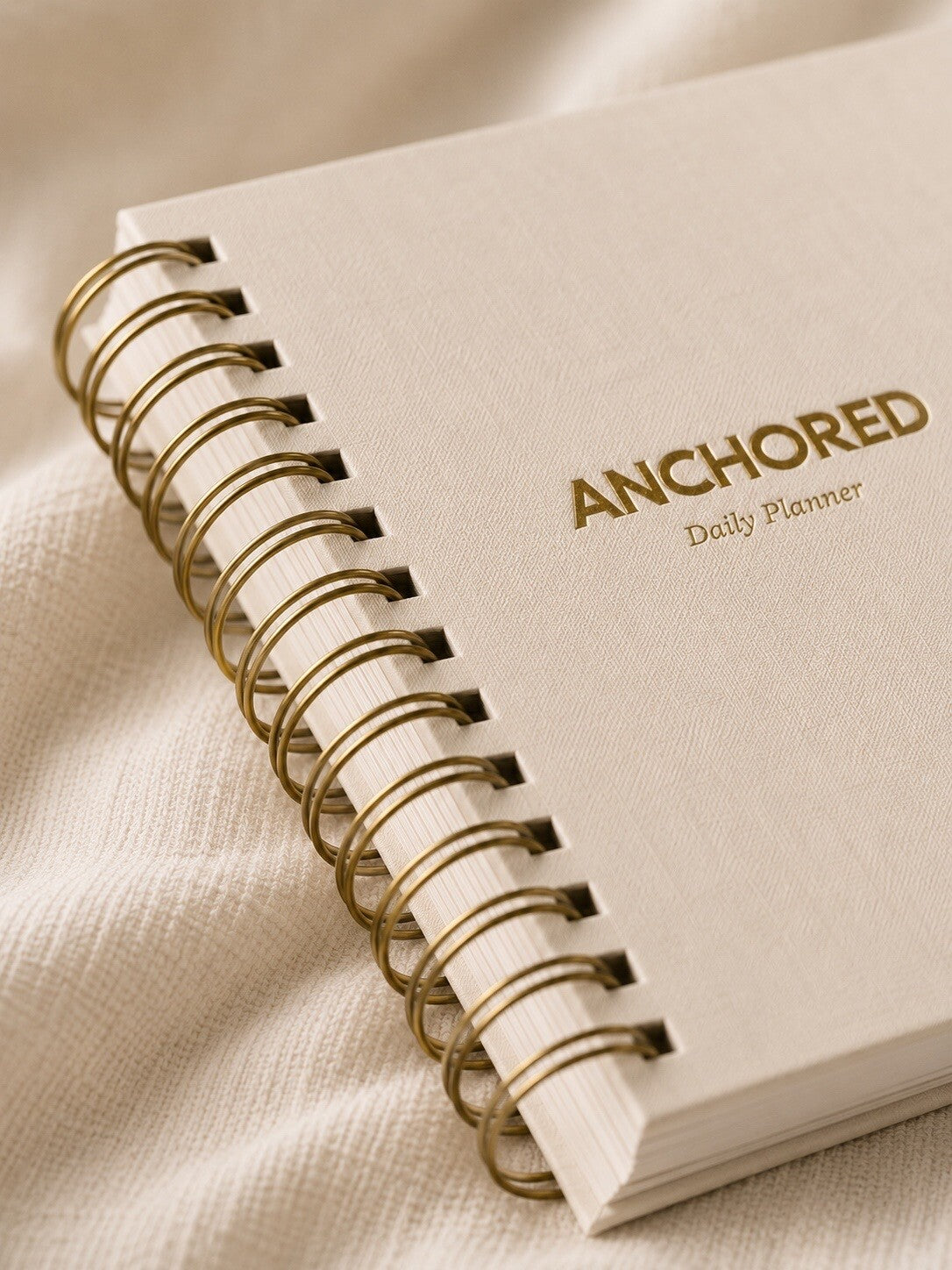 Close-up of the gold spiral binding and foil lettering on The Anchored Planner