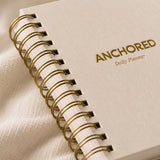 Close-up of the gold spiral binding and foil lettering on The Anchored Planner