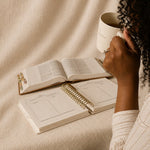A woman with coffee, her Bible and The Anchored Planner open in front of her