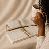A woman with coffee, her Bible and The Anchored Planner open in front of her