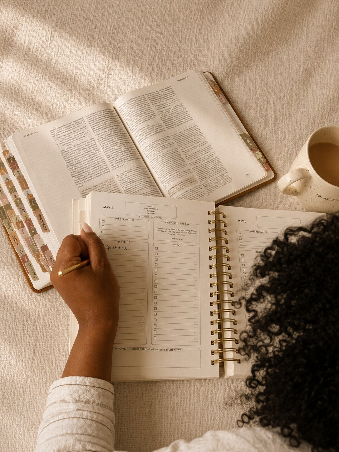 Hands writing in The Anchored Planner beside an open Bible